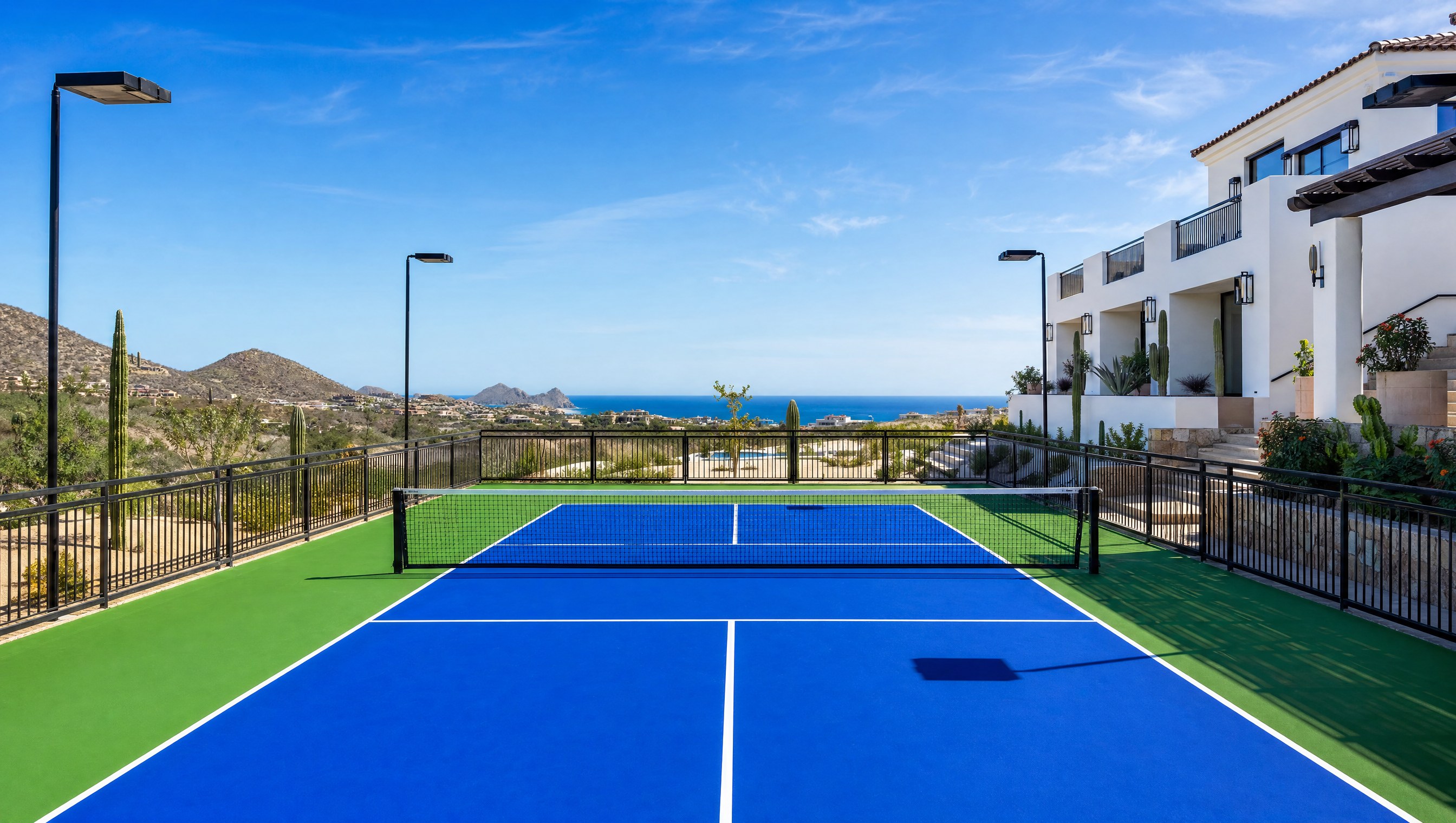 Cancha de pickleball profesional en club premium de Los Cabos con vista al Mar de Cortés, cactus desérticos y villa mediterránea — construcción CanchasdePickleball.mx