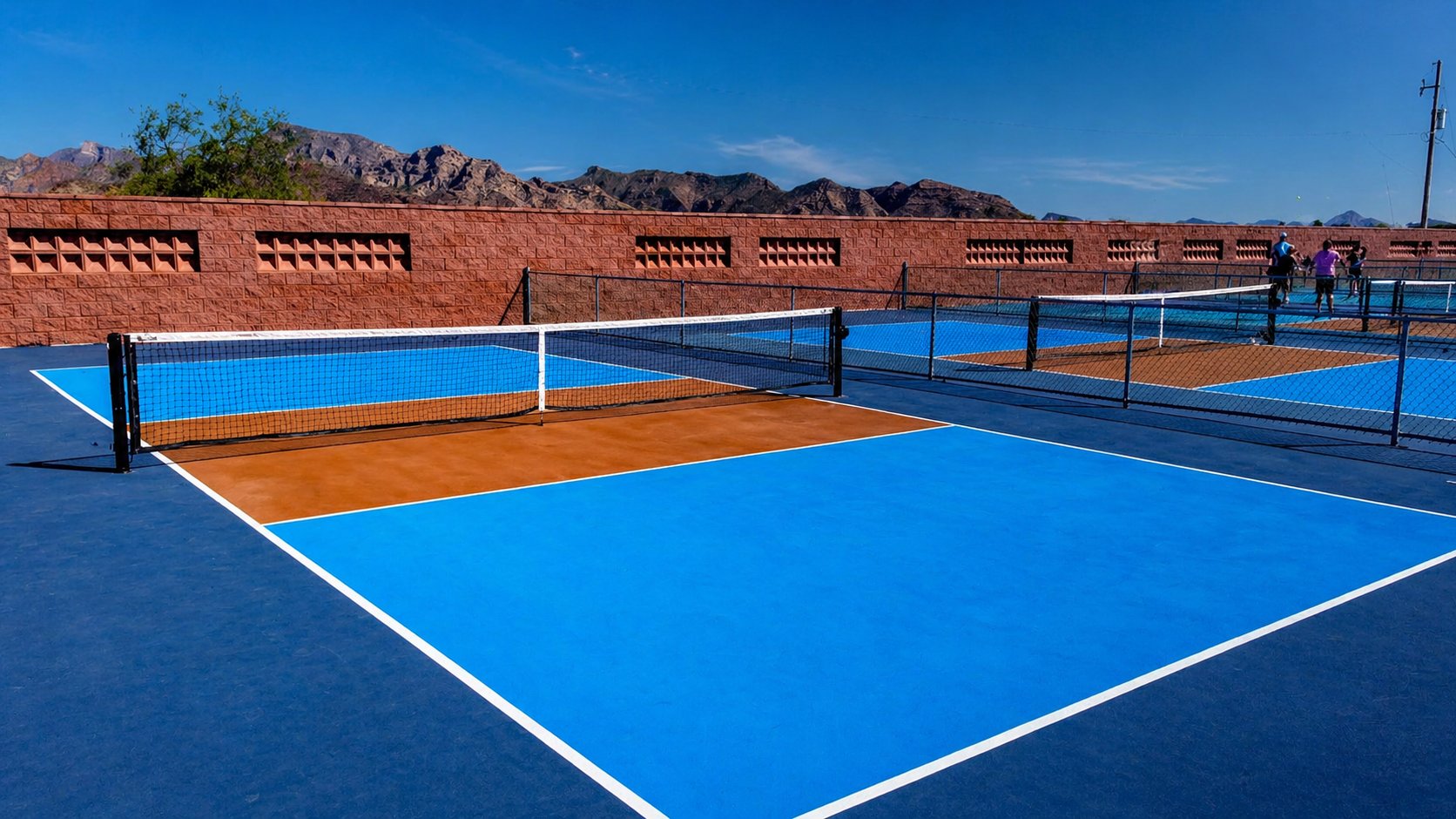 Club de pickleball profesional en Mexico con multiples canchas montanas al fondo iluminacion y jugadores activos